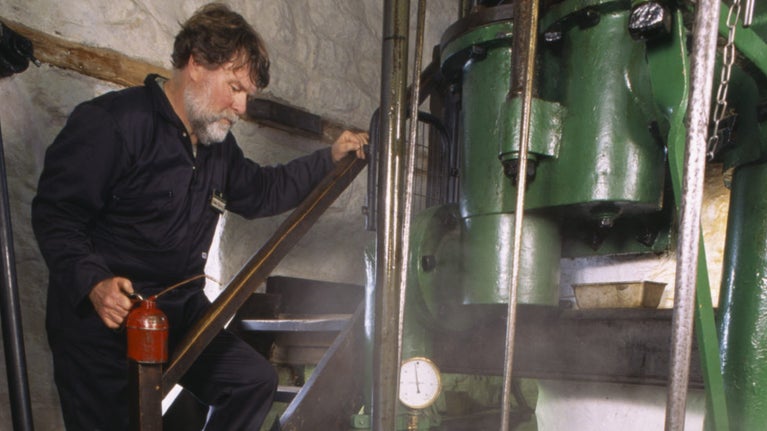 Chris Quick, a member of the 'Greasy Gang' volunteers, in the engine room of the Levant beam engine, St Just, Cornwall.
